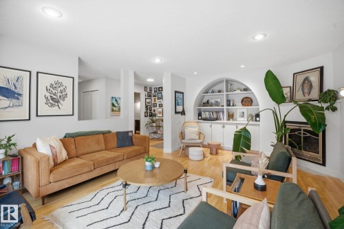 The living room features light hardwood floors, recessed lighting, and a white built-in arched shelving unit with cabinets - 7235 112 Street, Edmonton, AB - Indoor Photo Showing Living Room