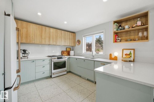 The kitchen features a white appliance suite, light wood tone upper cabinetry, and light blue lower cabinetry - 7235 112 Street, Edmonton, AB - Indoor Photo Showing Kitchen