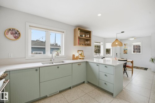 The kitchen features light green cabinetry, a white countertop, and light-colored tiled flooring - 7235 112 Street, Edmonton, AB - Indoor Photo Showing Kitchen