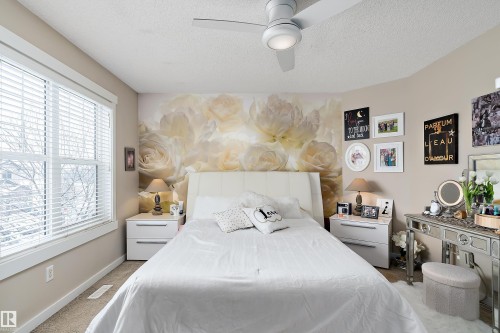 The room features a large window with blinds, a ceiling fan, and a light-colored accent wall behind the bed - 2914 18A Avenue, Edmonton, AB - Indoor Photo Showing Bedroom
