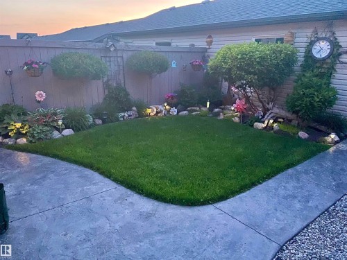 The property features an outdoor patio area with a neatly maintained lawn, surrounded by landscaped garden beds and decorative shrubs - 2914 18A Avenue, Edmonton, AB - Outdoor