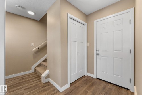 Entryway featuring wood-look flooring, a white paneled door, and a staircase with carpeted treads - 79 17635 58 Street, Edmonton, AB - Indoor Photo Showing Other Room