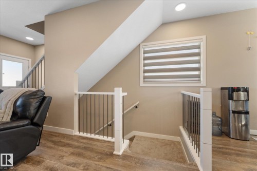 The property features a staircase with white railings and dark balusters, complemented by wood-look flooring - 79 17635 58 Street, Edmonton, AB - Indoor Photo Showing Other Room