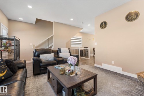 Spacious living area featuring recessed lighting, light-toned walls, and a staircase with white risers and dark handrails - 79 17635 58 Street, Edmonton, AB - Indoor Photo Showing Living Room