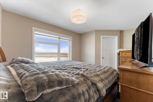 This room offers a window with an expansive view, light-colored walls, and a ceiling light fixture - 79 17635 58 Street, Edmonton, AB - Indoor Photo Showing Bedroom