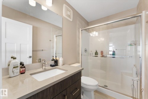 Bathroom featuring a modern vanity with a rectangular sink, a large mirror, and a glass-enclosed shower - 79 17635 58 Street, Edmonton, AB - Indoor Photo Showing Bathroom