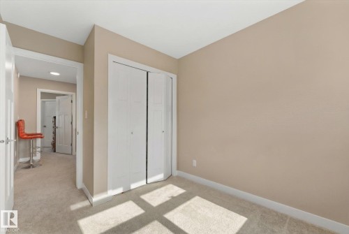 This room features light-colored walls and carpeting, with white bi-fold closet doors - 79 17635 58 Street, Edmonton, AB - Indoor Photo Showing Other Room