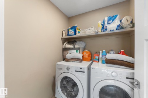The property features a dedicated laundry area with white front-loading appliances and shelving for storage - 79 17635 58 Street, Edmonton, AB - Indoor Photo Showing Laundry Room