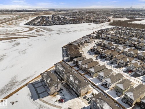 Aerial view of a developed residential area featuring various housing styles and an expansive undeveloped snow-covered area - 79 17635 58 Street, Edmonton, AB - Outdoor With View
