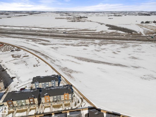 Aerial view showcasing the property's location near a highway and expansive snow-covered fields - 79 17635 58 Street, Edmonton, AB - Outdoor With View