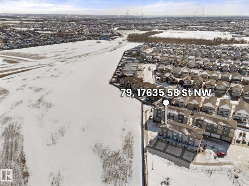 Aerial view showcasing the property within a developed neighborhood, featuring many residential buildings and open, snow-covered fields - 79 17635 58 Street, Edmonton, AB - Outdoor With View