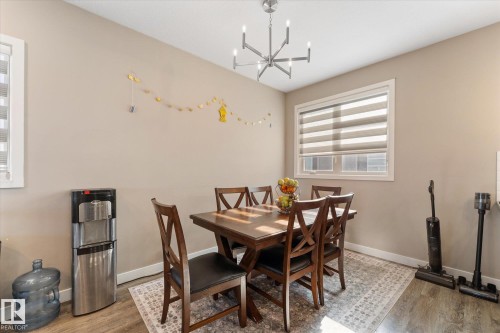 Dining area featuring neutral toned walls, a window with horizontal blinds, and a contemporary chandelier - 79 17635 58 Street, Edmonton, AB - Indoor Photo Showing Dining Room