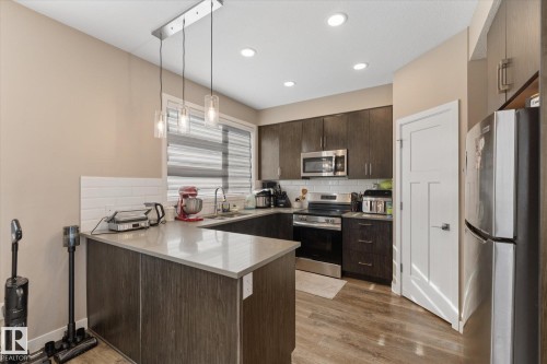 The kitchen features dark wood cabinetry, stainless steel appliances, and a light-colored countertop - 79 17635 58 Street, Edmonton, AB - Indoor Photo Showing Kitchen