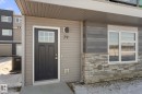 The property features a dark-colored entry door with decorative glass, complemented by light-colored siding and a stone facade - 79 17635 58 Street, Edmonton, AB  - Outdoor With Exterior 
