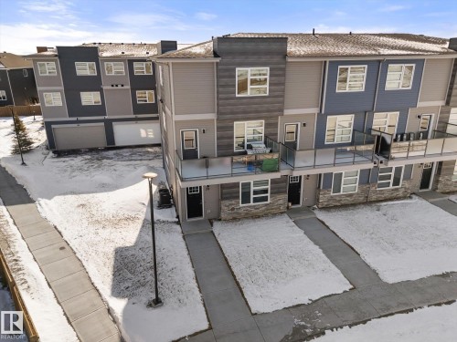 The property features a modern exterior with varied siding materials and a balcony with glass railings - 79 17635 58 Street, Edmonton, AB - Outdoor