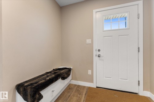 The entryway features a white front door with a window, neutral-toned walls, and wood-style flooring - 79 17635 58 Street, Edmonton, AB - Indoor