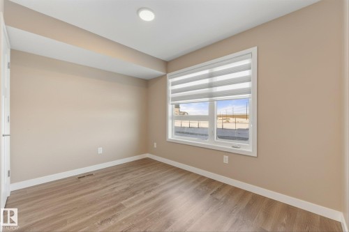 This room features light-colored walls, light wood-style flooring, and a window with blinds providing natural light - 79 17635 58 Street, Edmonton, AB - Indoor Photo Showing Other Room