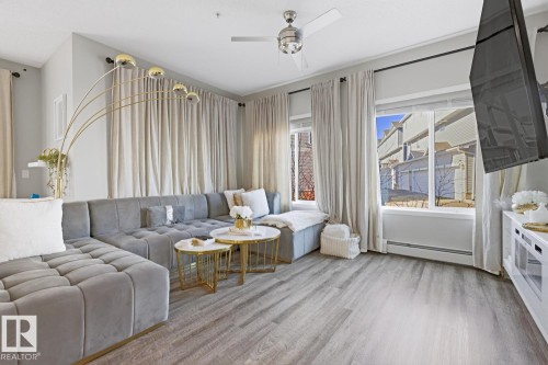 The living area features light-colored walls, wood-look flooring, and a ceiling fan - 155 1818 Rutherford Road, Edmonton, AB - Indoor Photo Showing Living Room