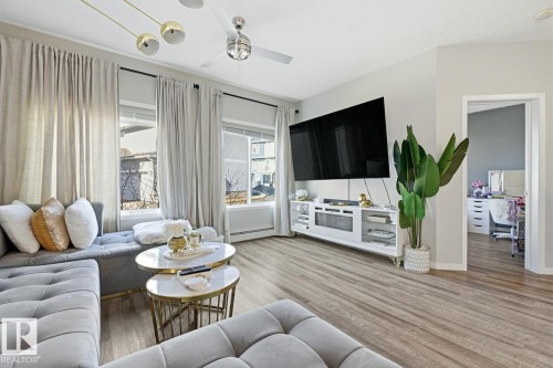 Living area featuring light wood-style flooring, a ceiling fan, and large windows with privacy blinds - 155 1818 Rutherford Road, Edmonton, AB - Indoor Photo Showing Living Room