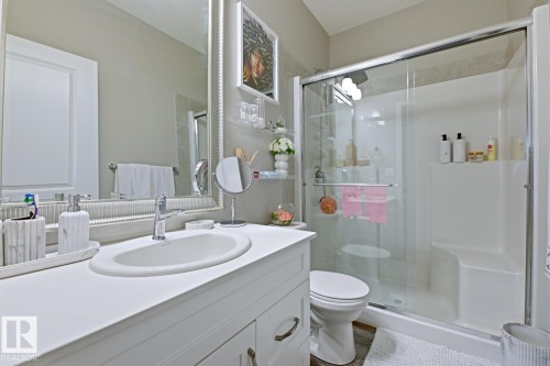 Well-appointed bathroom featuring a vanity with an integrated sink, a toilet, and a stand-up shower with a glass enclosure and a built-in bench - 155 1818 Rutherford Road, Edmonton, AB - Indoor Photo Showing Bathroom