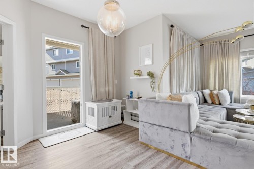 Living area featuring hard surface flooring, light-colored walls, and a glass-paneled door opening to an outdoor patio area - 155 1818 Rutherford Road, Edmonton, AB - Indoor