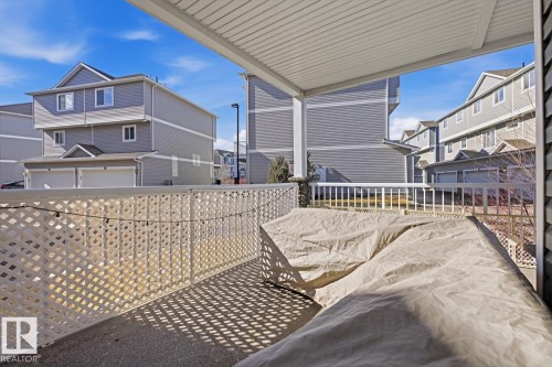 The property features a covered patio with a white lattice railing and concrete flooring, offering an outdoor living space - 155 1818 Rutherford Road, Edmonton, AB - Outdoor