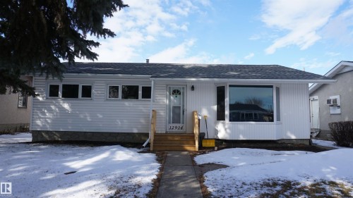 The property features a white exterior, a grey roof, and a front entry with wooden steps - 12924 135A Avenue, Edmonton, AB - Outdoor