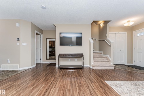 The property features hardwood style flooring, a carpeted staircase with a white railing, and a white front door with window inserts - 31 4029 Orchards Drive, Edmonton, autreother - Indoor
