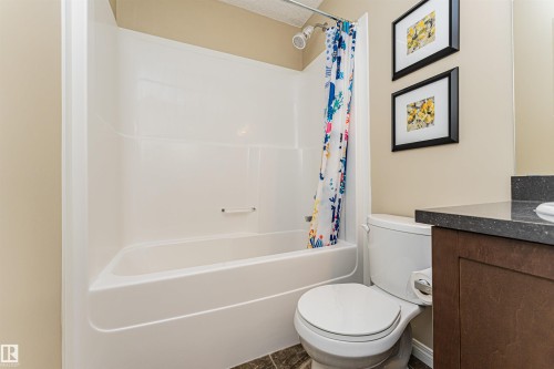 Bathroom featuring a white shower and bathtub combination unit, a toilet, and a vanity with a dark countertop - 31 4029 Orchards Drive, Edmonton, autreother - Indoor Photo Showing Bathroom
