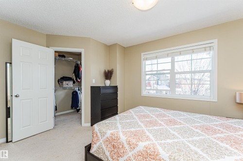 The property features a bedroom with a window providing outdoor views, a walk-in closet with shelving and hanging space, and carpeted flooring - 31 4029 Orchards Drive, Edmonton, autreother - Indoor Photo Showing Bedroom
