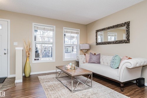 The living area features warm-toned walls, dark wood-style flooring, and an area rug - 31 4029 Orchards Drive, Edmonton, autreother - Indoor Photo Showing Living Room