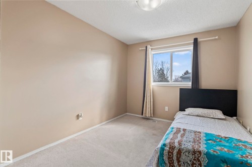 This room features light-colored walls and carpeting, a window with exterior views, and a ceiling light fixture - 92 4350 23 Street Nw, Edmonton, AB - Indoor Photo Showing Bedroom