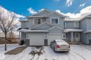 The property features light blue siding, white trim, and a white garage door - 92 4350 23 Street Nw, Edmonton, AB  - Outdoor With Facade 