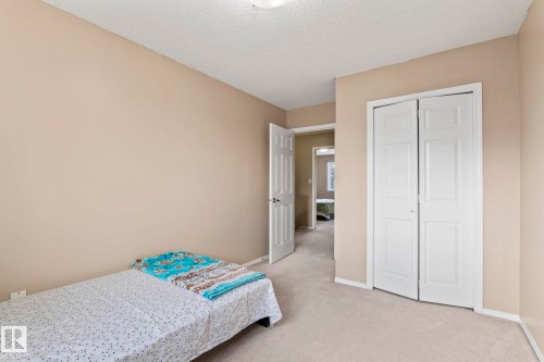 This room features neutral-toned walls, light-colored carpeting, and a white bi-fold closet door - 92 4350 23 Street Nw, Edmonton, AB - Indoor Photo Showing Bedroom