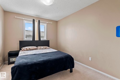 The property features a bedroom with neutral-toned walls, carpeted flooring, and a window providing natural light - 92 4350 23 Street Nw, Edmonton, AB - Indoor Photo Showing Bedroom