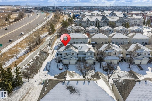 Aerial view of the property and surrounding neighborhood, featuring a snowy landscape and a nearby highway - 92 4350 23 Street Nw, Edmonton, AB - Outdoor With View