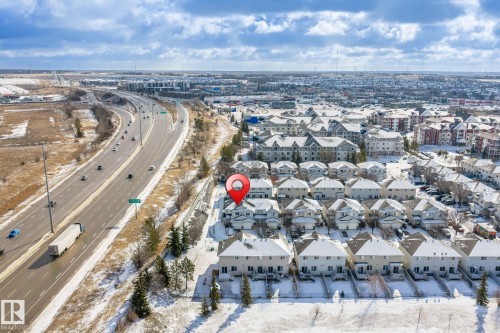 Aerial view of the property and surrounding neighborhood, featuring a highway with vehicles and residential buildings with snow-covered roofs - 92 4350 23 Street Nw, Edmonton, AB - Outdoor With View