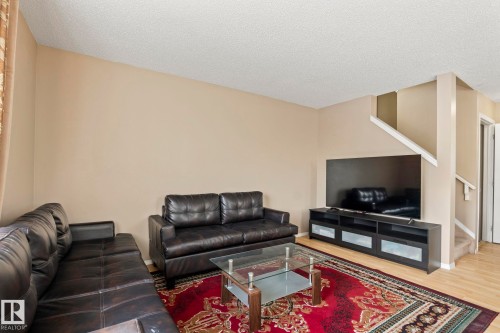 The living room features a beige wall, light-colored flooring, and a staircase with white railings - 92 4350 23 Street Nw, Edmonton, AB - Indoor Photo Showing Living Room