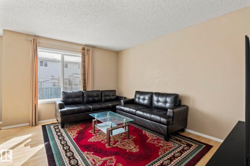 Living area featuring light-colored walls, light wood-style flooring, and a large window providing natural light - 92 4350 23 Street Nw, Edmonton, AB - Indoor Photo Showing Living Room
