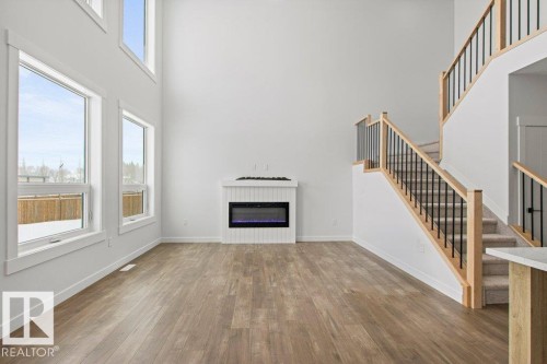 The property features high ceilings, extensive windows providing abundant natural light, and a contemporary fireplace - 5018 53 Avenue, Calmar, AB - Indoor With Fireplace