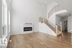 Living area featuring high ceilings, light-toned flooring, a fireplace, and large windows - 