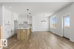 Open concept living area featuring light wood tone flooring and white walls - 