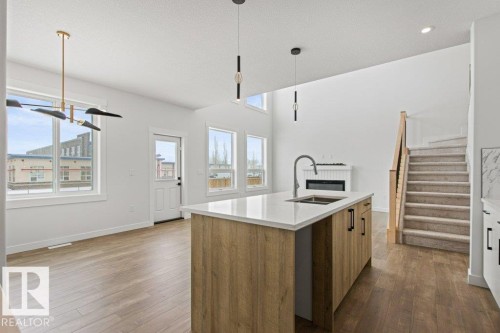The property features an open living space with light wood flooring and white walls, illuminated by natural light from several windows - 5018 53 Avenue, Calmar, AB - Indoor Photo Showing Kitchen With Double Sink With Upgraded Kitchen