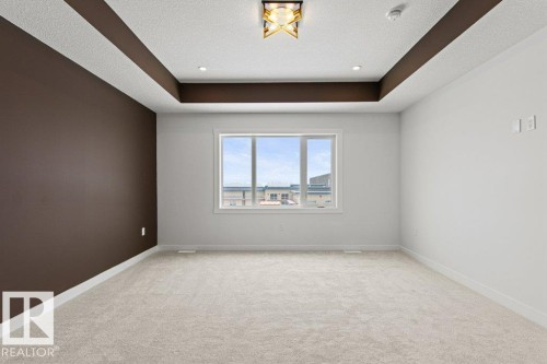 Spacious room featuring light-colored carpeting, a large window, and a tray ceiling with recessed lighting and a central light fixture - 5018 53 Avenue, Calmar, AB - Indoor Photo Showing Other Room