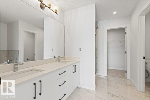 Bathroom featuring a double vanity with light-colored countertops, undermount sinks, and chrome faucets - 5018 53 Avenue, Calmar, AB - Indoor Photo Showing Bathroom