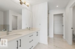 Bathroom featuring a double vanity with light-colored countertops, undermount sinks, and chrome faucets - 