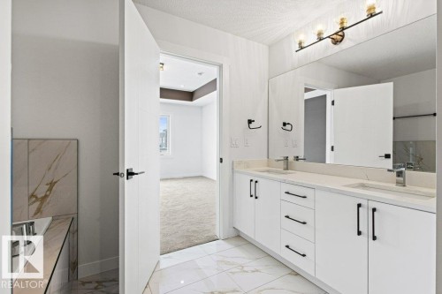 The bathroom features a double vanity with white cabinetry, light-colored countertops, and modern dark hardware - 5018 53 Avenue, Calmar, AB - Indoor Photo Showing Bathroom