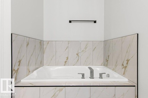 Bathroom featuring a built-in bathtub with a tile surround and chrome fixtures - 5018 53 Avenue, Calmar, AB - Indoor Photo Showing Bathroom