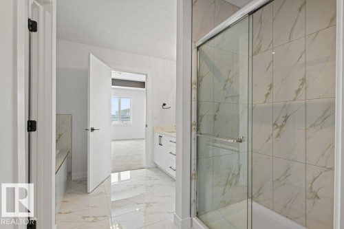 This bathroom features a shower with sliding glass doors and large format marble-look wall tiles - 5018 53 Avenue, Calmar, AB - Indoor Photo Showing Bathroom