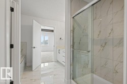 This bathroom features a shower with sliding glass doors and large format marble-look wall tiles - 